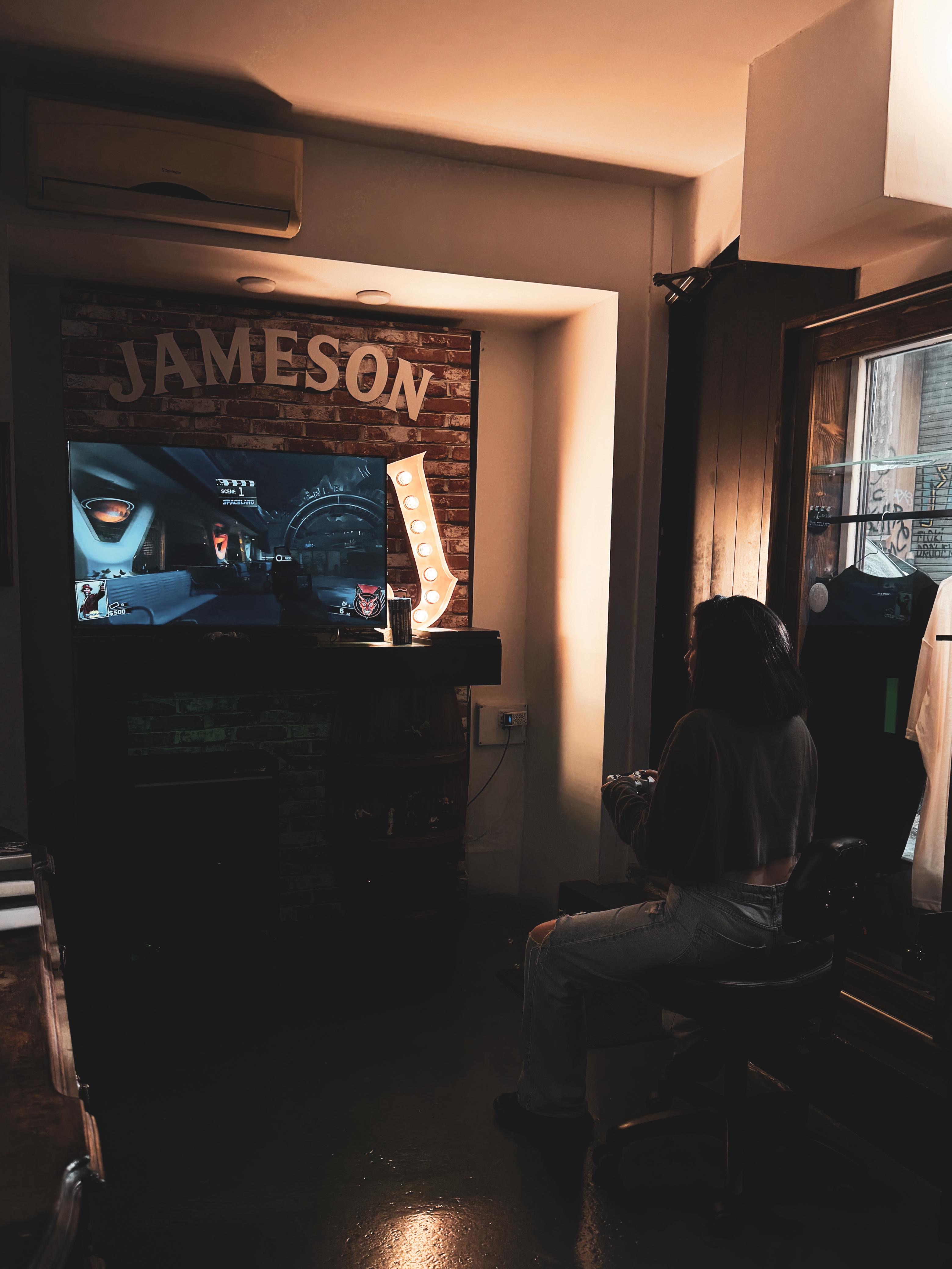 Lounge gaming setup with TV, controller, and Jameson sign